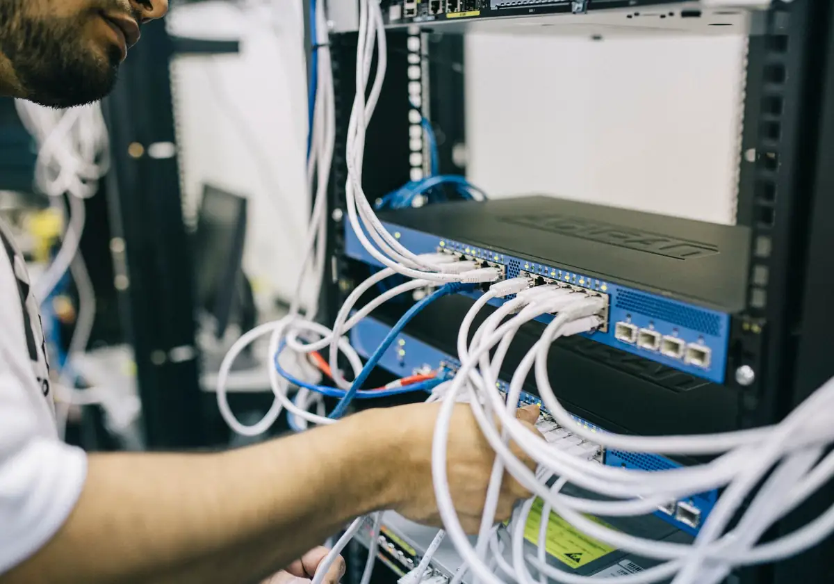 Técnico organizando cabos em um rack de rede
